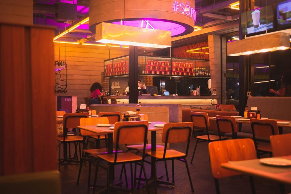 Cozy restaurant interior with wooden seating and vibrant neon lights creating a warm ambiance.